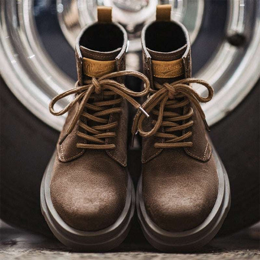 Pair of brown leather boots with laces on a reflective surface