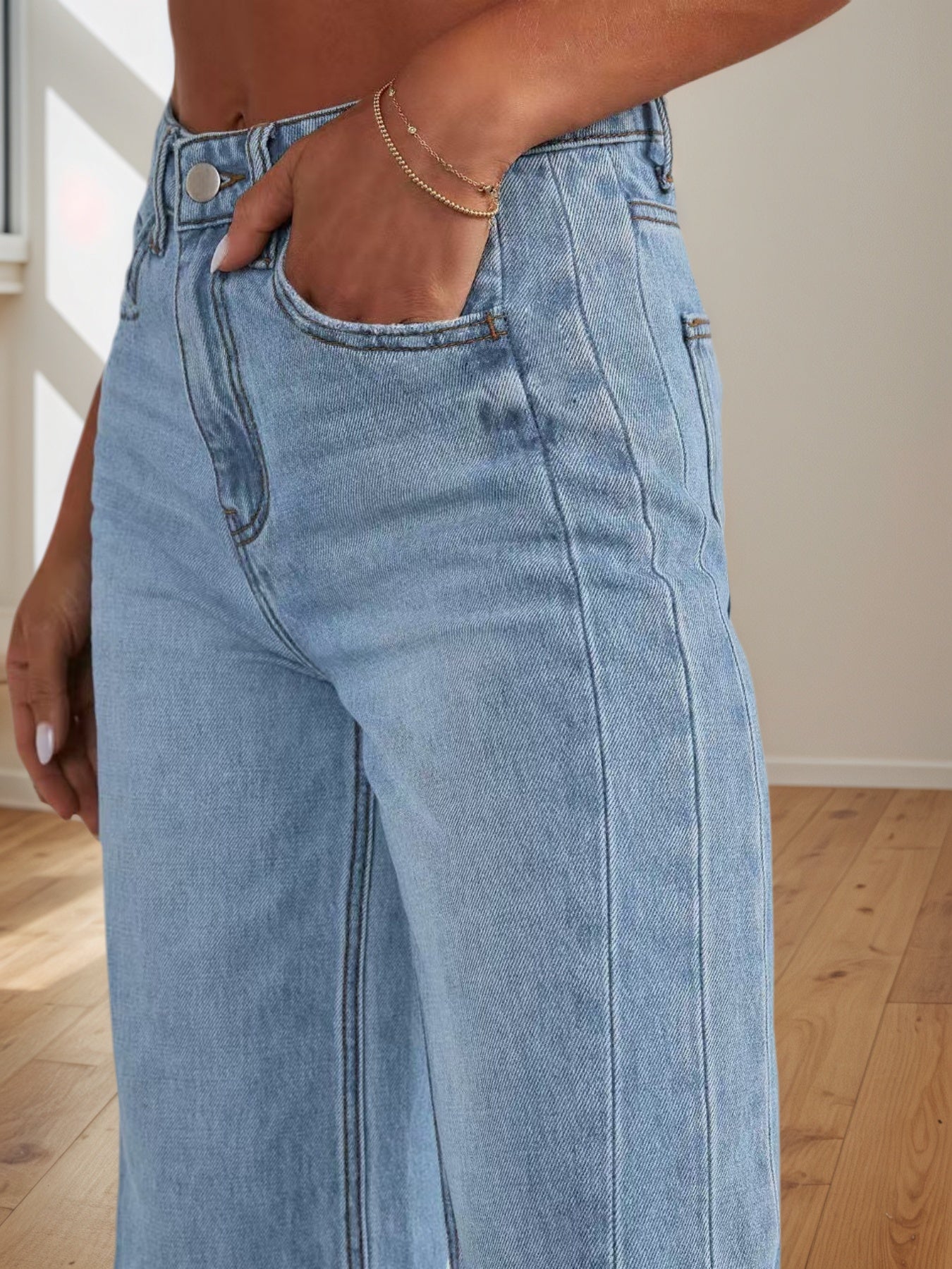 Women's light blue denim pants close-up: front pocket, button waistband, belt loops.