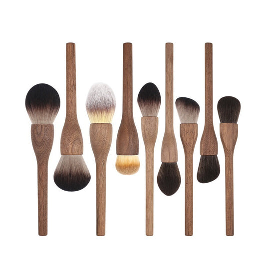 Set of makeup brushes with wooden handles and black to white bristle tips on a white background
