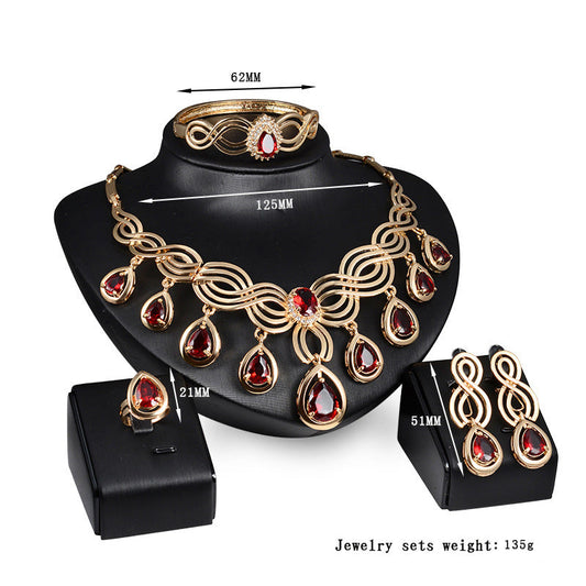 Gold-tone jewelry set with red teardrop gems: necklace, bracelet, and matching earrings