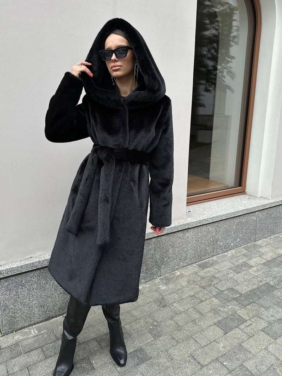 Woman wearing a black coat with a hood in an urban setting