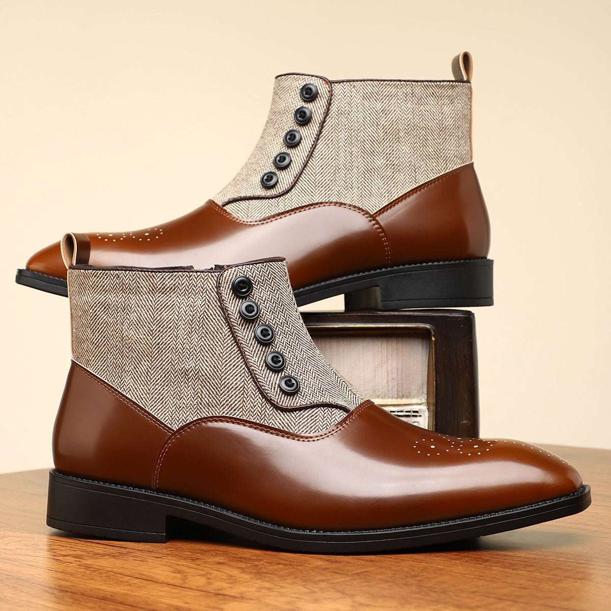 Brown leather boots with beige fabric panels on a wooden surface