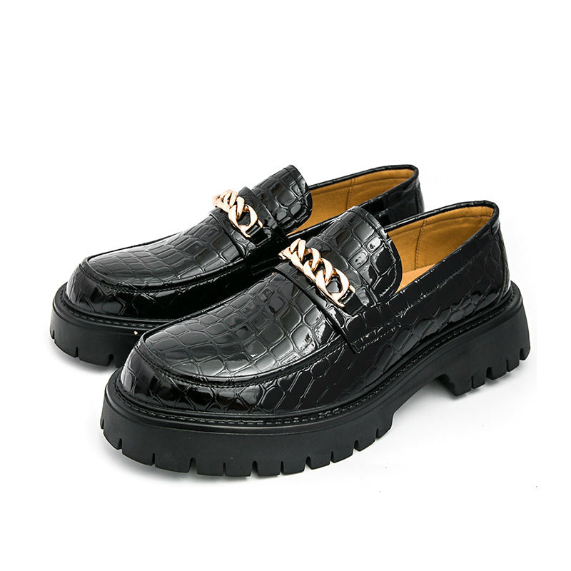 Black crocodile-patterned loafers with gold chain details on a white background