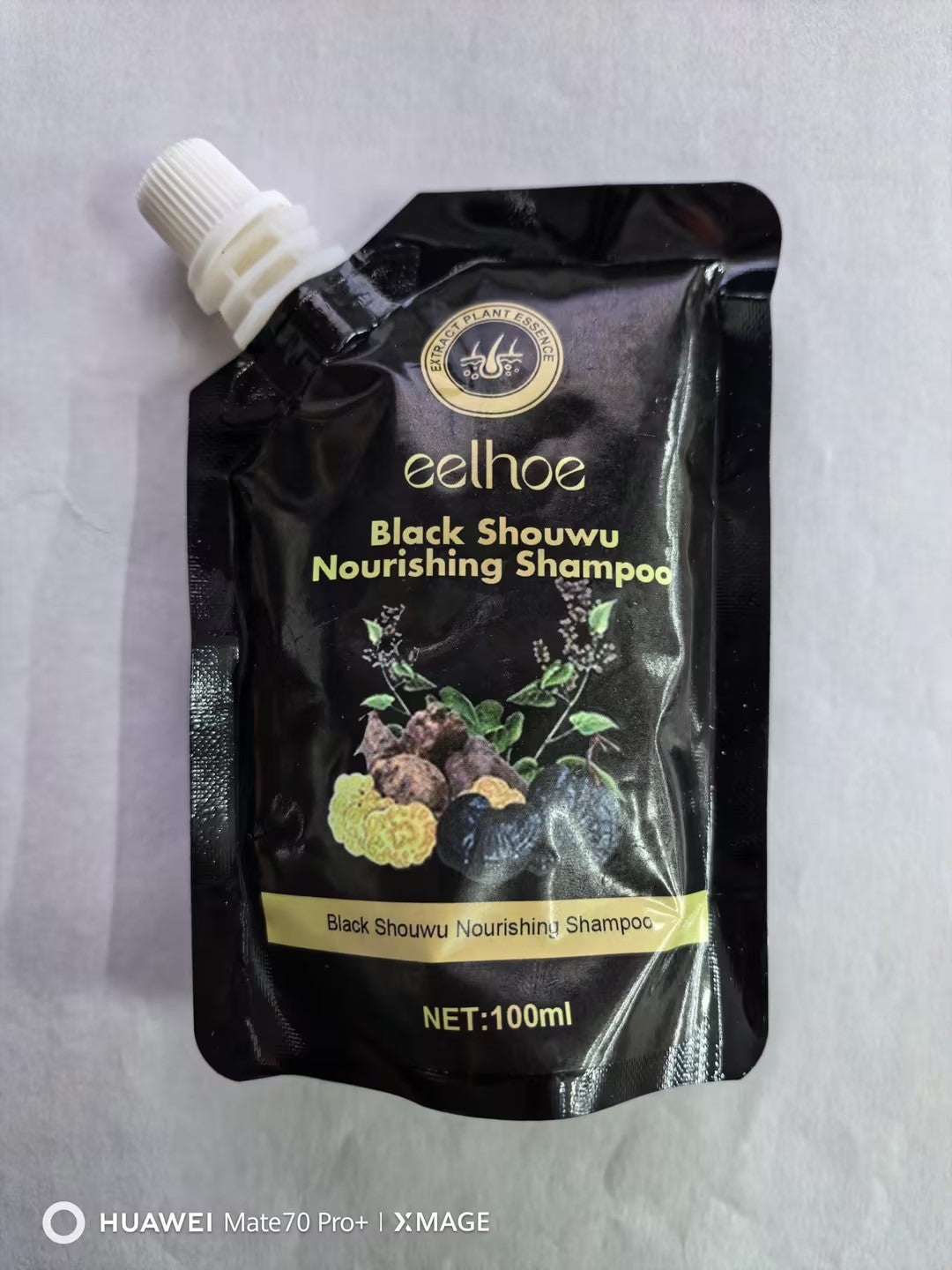 Black shampoo packaging with branding and product details on a gray background