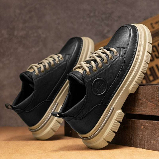 Black leather boots with beige accents on a wooden surface