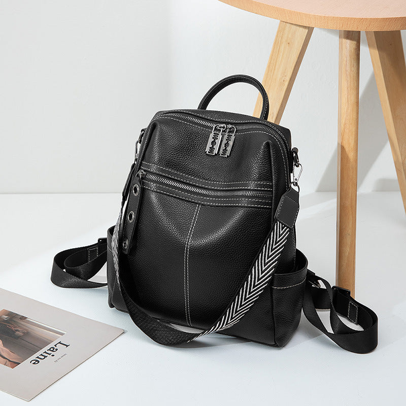 Black mini backpack with top handle, front zipper pocket, and crossbody strap with chevron trim.