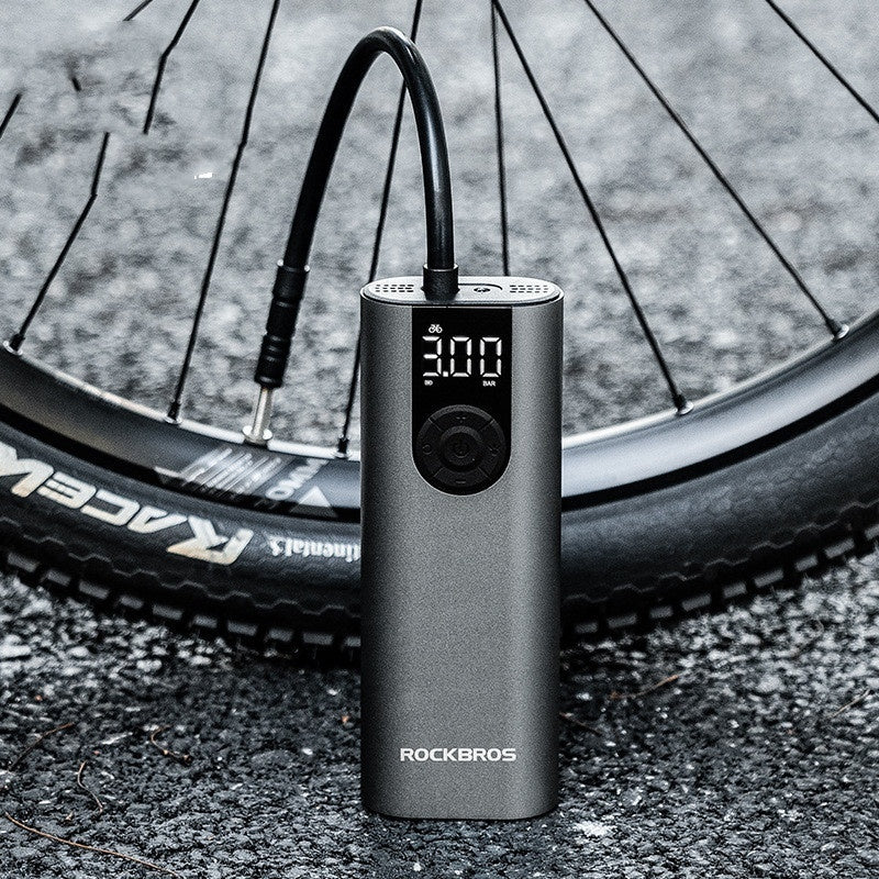 Bicycle tire being pumped up by a ROCKBROS air pump on a road.