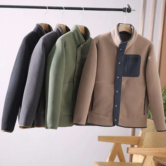 Four jackets in different colors hanging on a rack against a white wall.