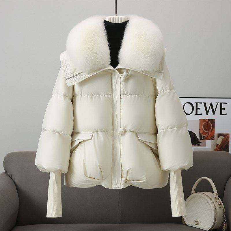White puffer jacket with fur hood on a gray sofa