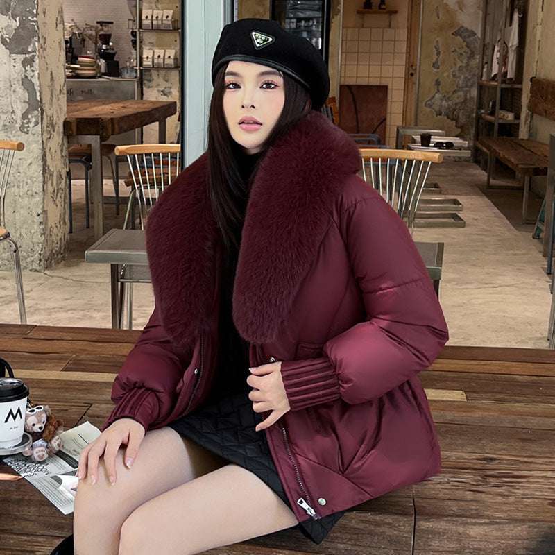 Woman wearing a burgundy coat with fur collar sitting in a cafe.