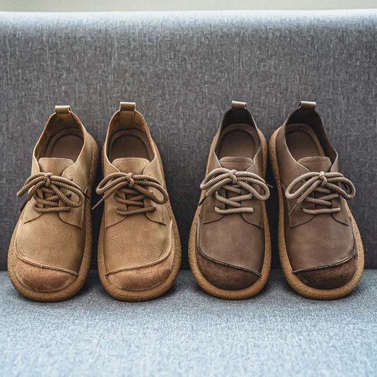 Pair of brown suede shoes with laces on a textured surface