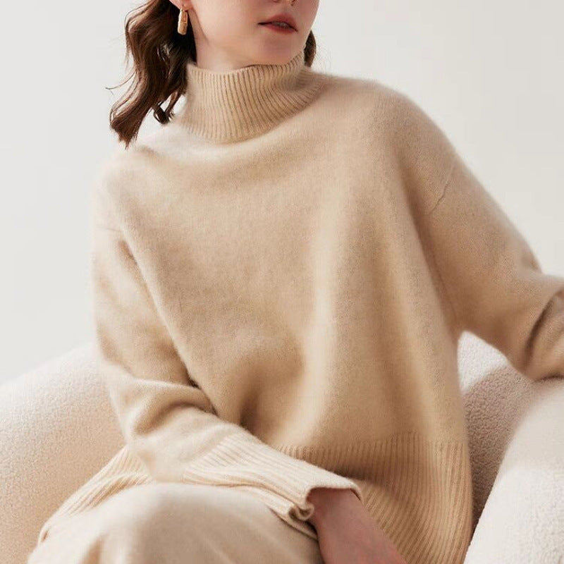 Person wearing a beige sweater sitting on a white couch.
