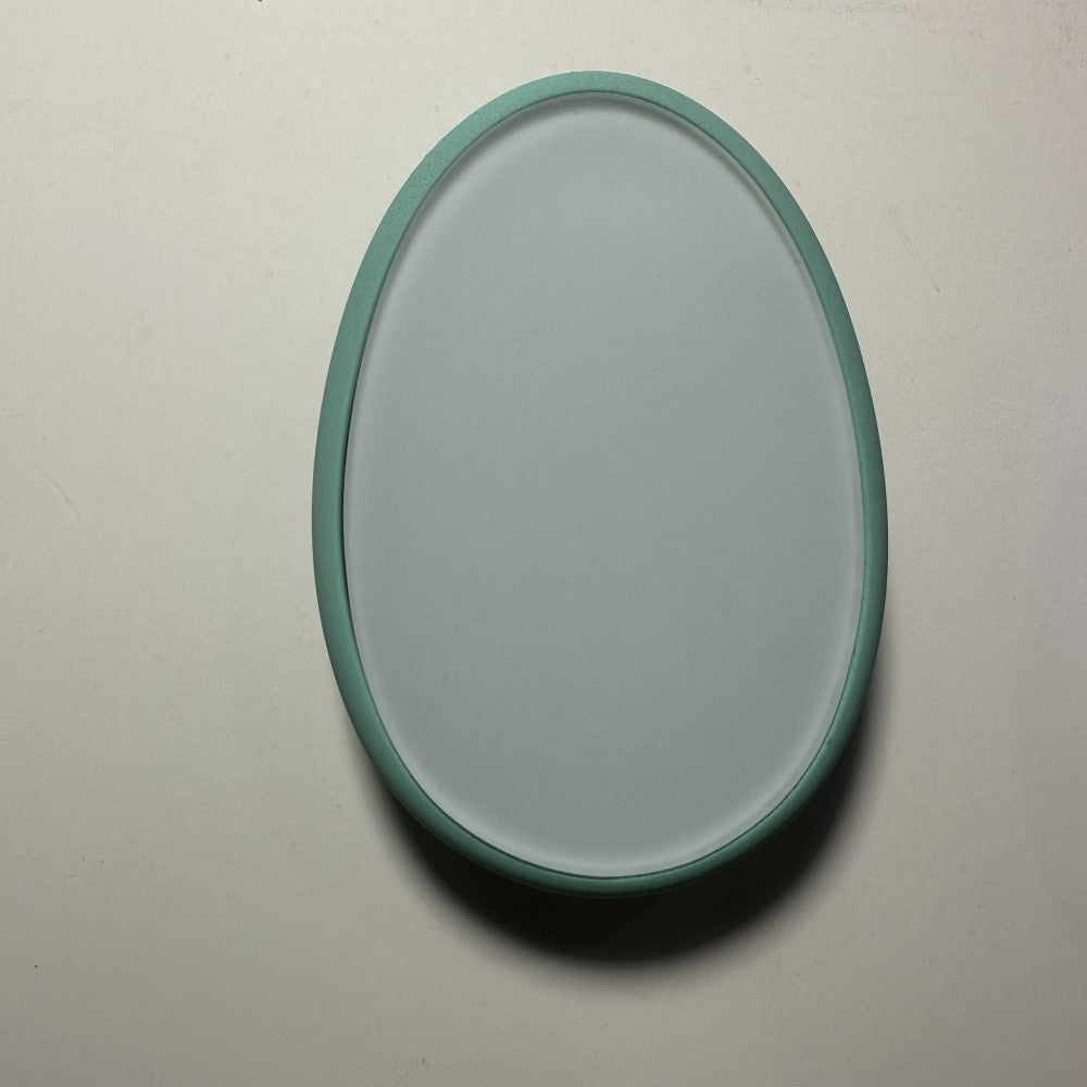 Teal nano-glass hair remover with plain oval glass face in raised frame.