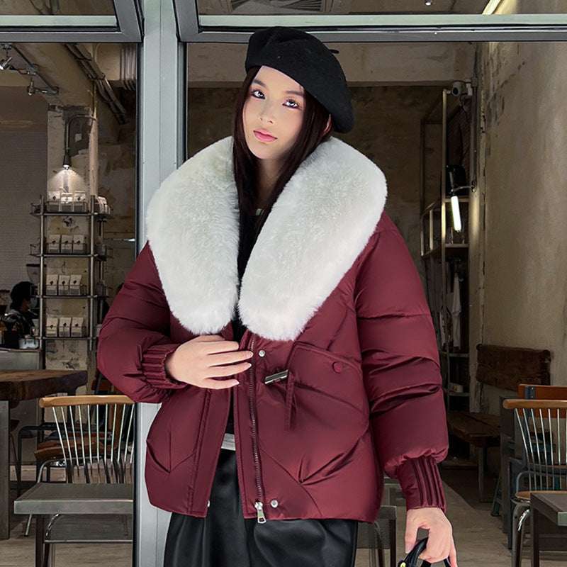 Person wearing a maroon coat with a white fur collar in an indoor setting