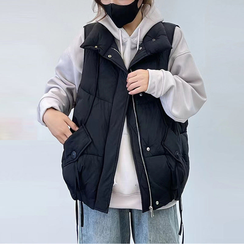 Person wearing a black puffer vest over a light gray hoodie on a light blue background