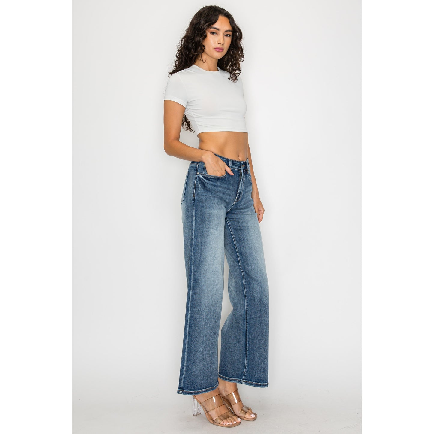 High-waisted flare jeans in medium blue wash, worn by model standing front with wide legs.