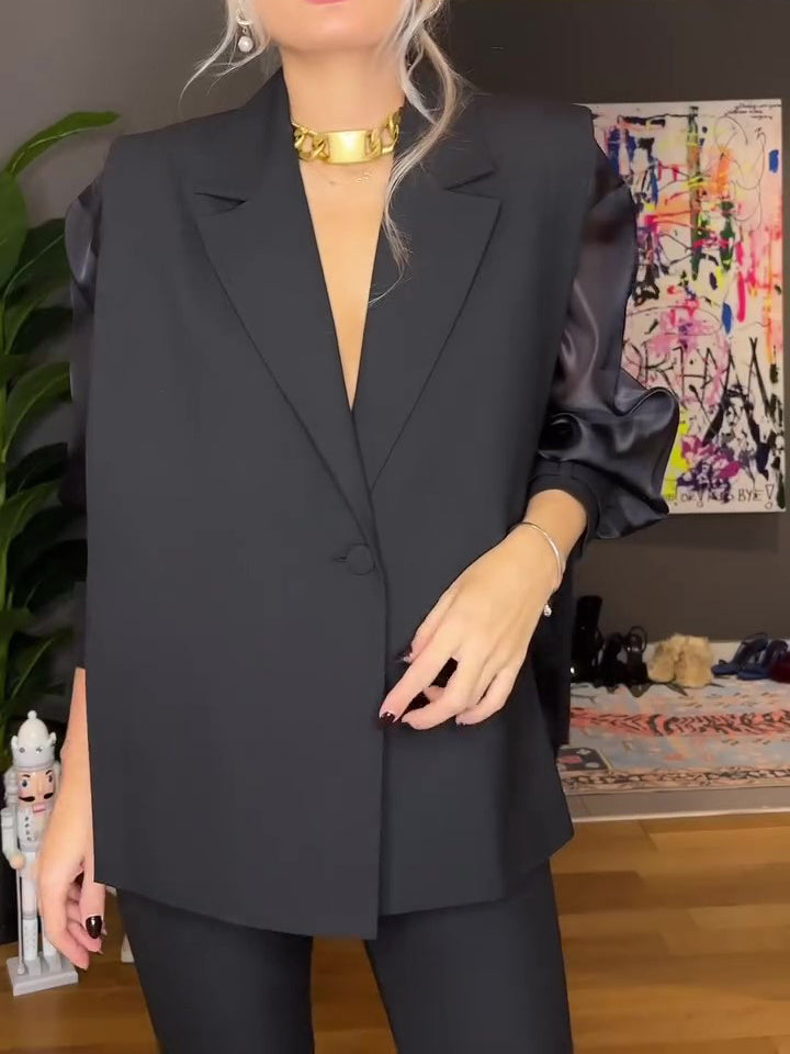Person wearing a black suit with a colorful abstract painting in the background