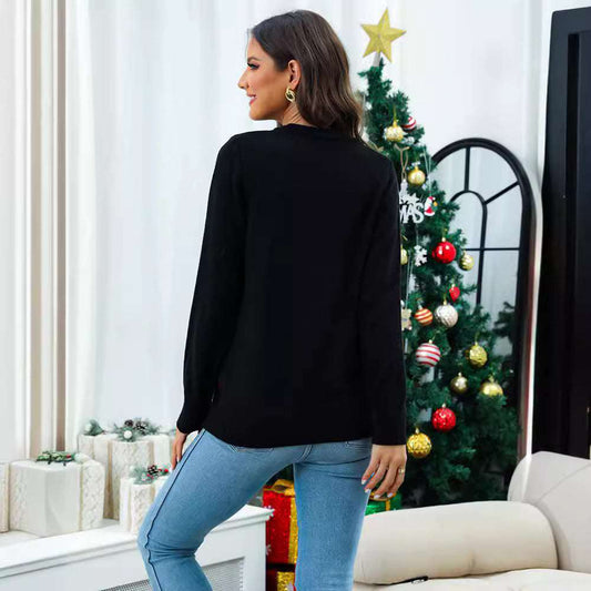 Woman wearing a black sweater and blue jeans standing in a living room with a decorated Christmas tree.