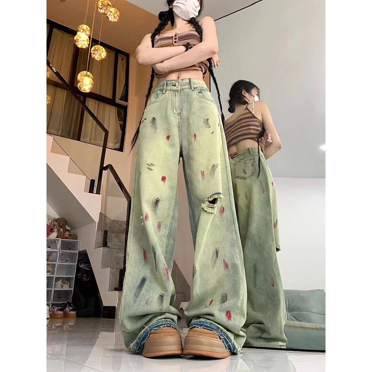 Person wearing light green distressed jeans in a room with modern decor.