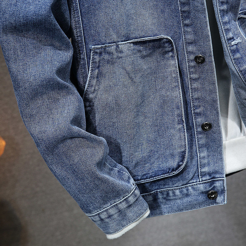 Close-up of a blue denim jacket with a pocket and buttons on a gray background