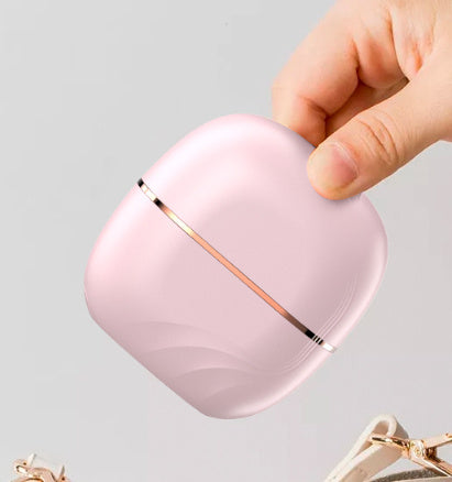 Pink wireless earbuds case with rose gold accents held by a hand on a light gray background