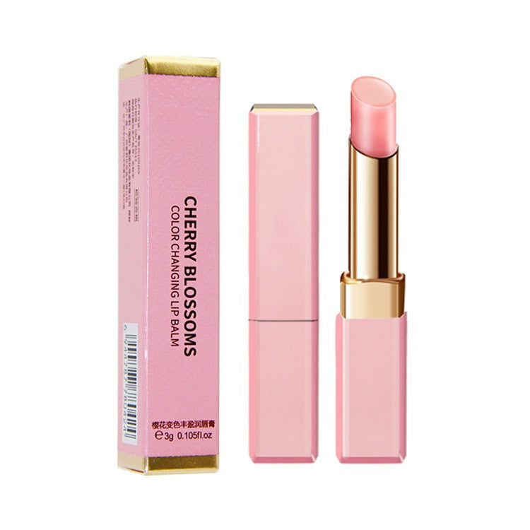 Pink lip balm with gold accents and packaging on a white background