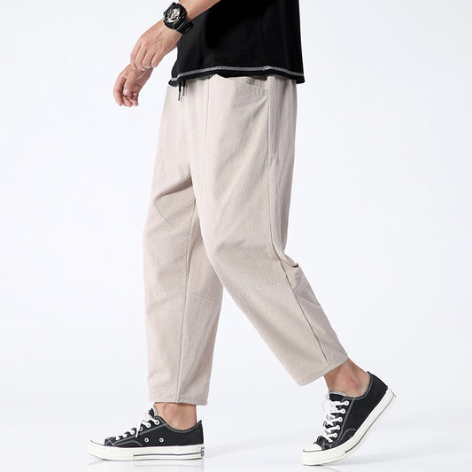 Person wearing beige pants and black sneakers on a white background