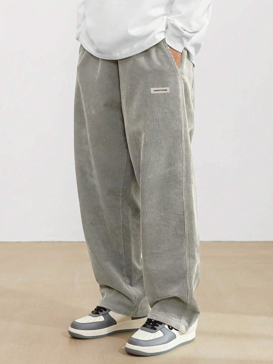 Person wearing gray wide-leg pants and white sneakers on a plain background