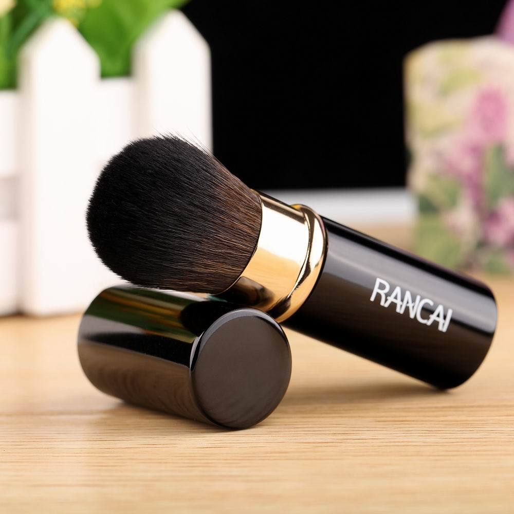 Makeup brush with black handle and gold accents on a wooden surface, featuring the brand 'RANCAI'.