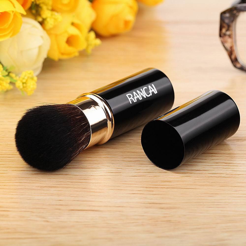 Makeup brush with black bristles and gold accents on a wooden surface, featuring the brand 'RANCAI'.
