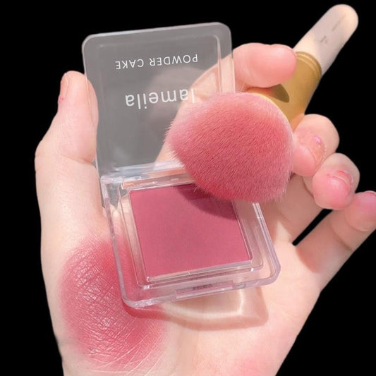 Hand holding a pink blush with a brush, brand 'Lamelia' visible