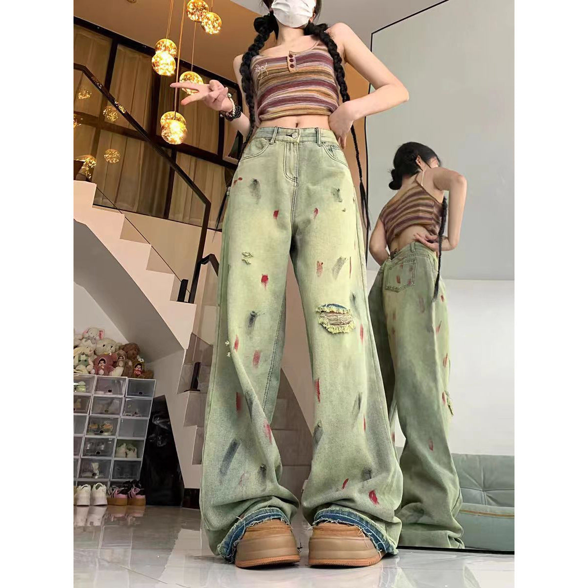 Person wearing a striped crop top and distressed light green jeans in an indoor setting.