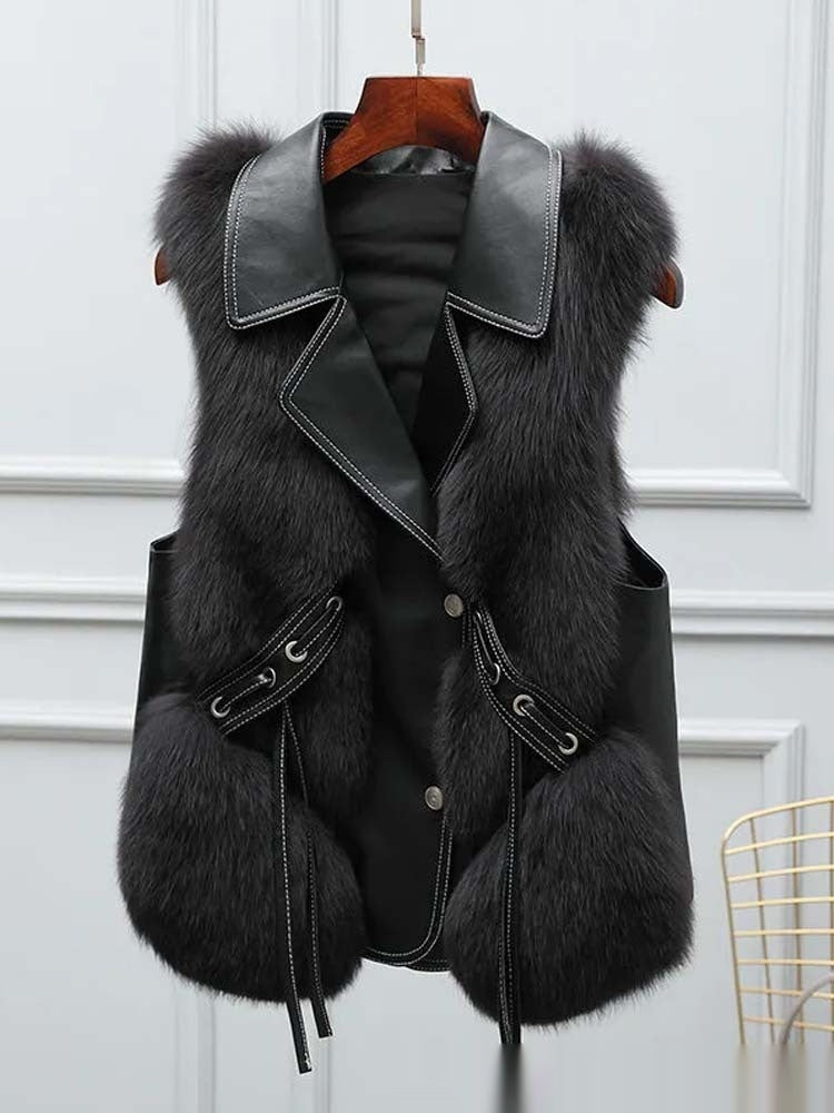 Black fur vest with leather accents on a hanger against a white background