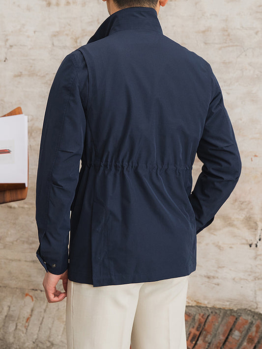 Person wearing a navy jacket standing against a textured wall.