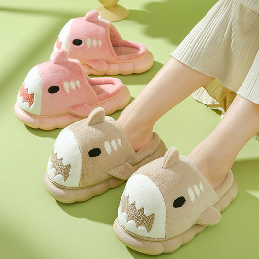 A pair of pink shark-themed slippers with thick soles being worn on a green background.