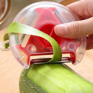 Hand using a red and white three-in-one peeler to peel green vegetables.