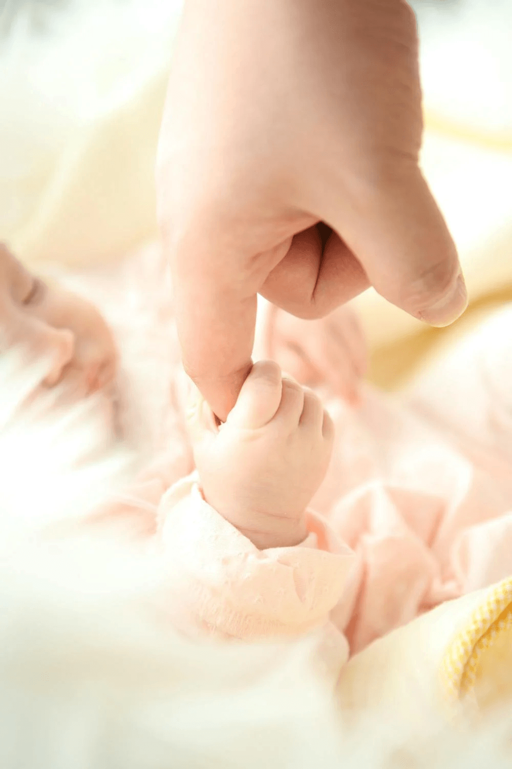 A mother's hand gently holding her baby's hand, symbolizing love in the Baby & Mother collection.