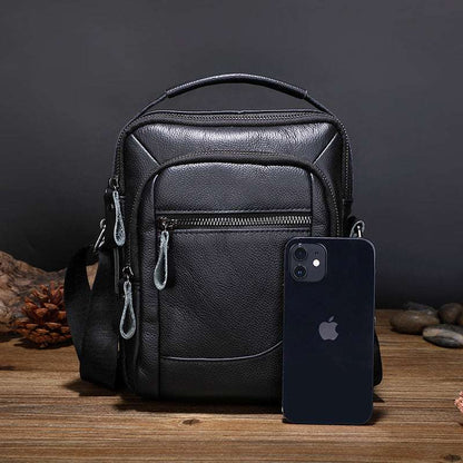 Men's leather business bag, black front zipper pocket with phone resting against it