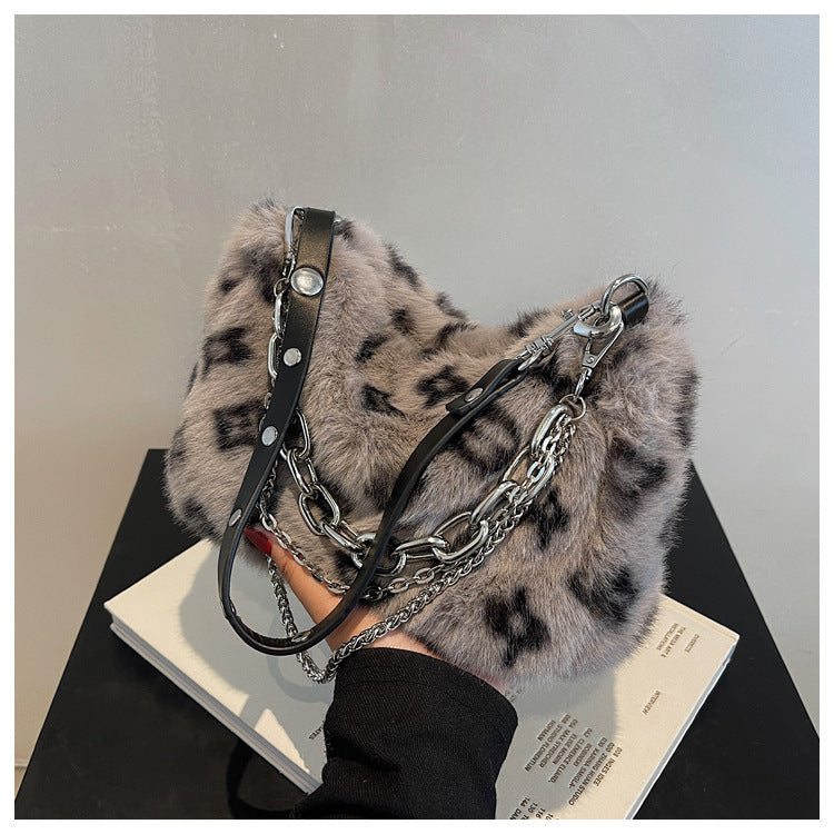 Grey plush leopard print bag with silver chain and black leather strap, close-up angle
