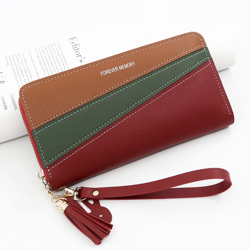 Long wallet with wrist strap, brown top, green stripe, and red panels with tassel.
