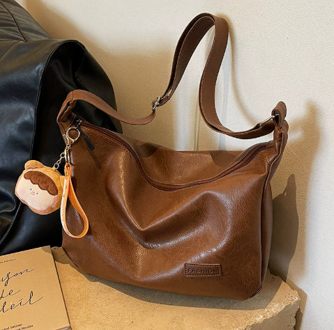 Brown hobo shoulder bag with long strap and hanging charm keychain