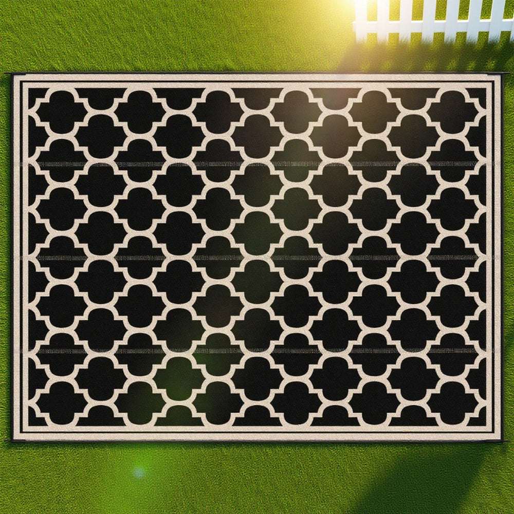 Reversible outdoor rug close-up with black-and-cream quatrefoil pattern and border