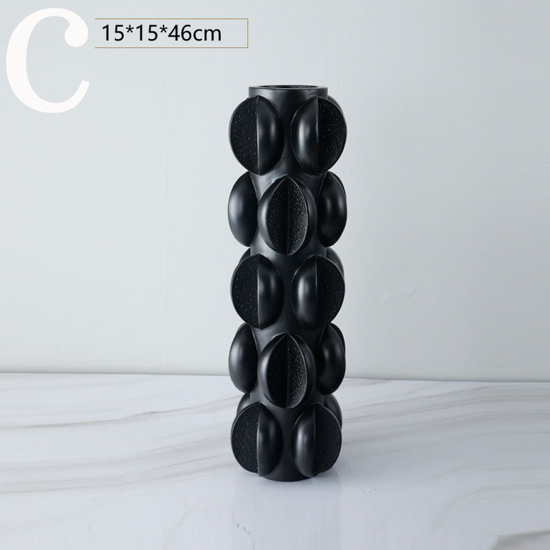 Tall sculptural black resin vase with layered oval pods and open mouth
