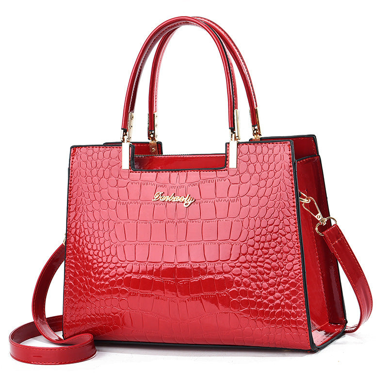 Red croc-texture tote with top handles and shoulder strap, structured rectangular bag