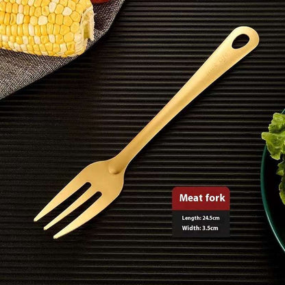 Gold meat fork on a black surface with corn and salad