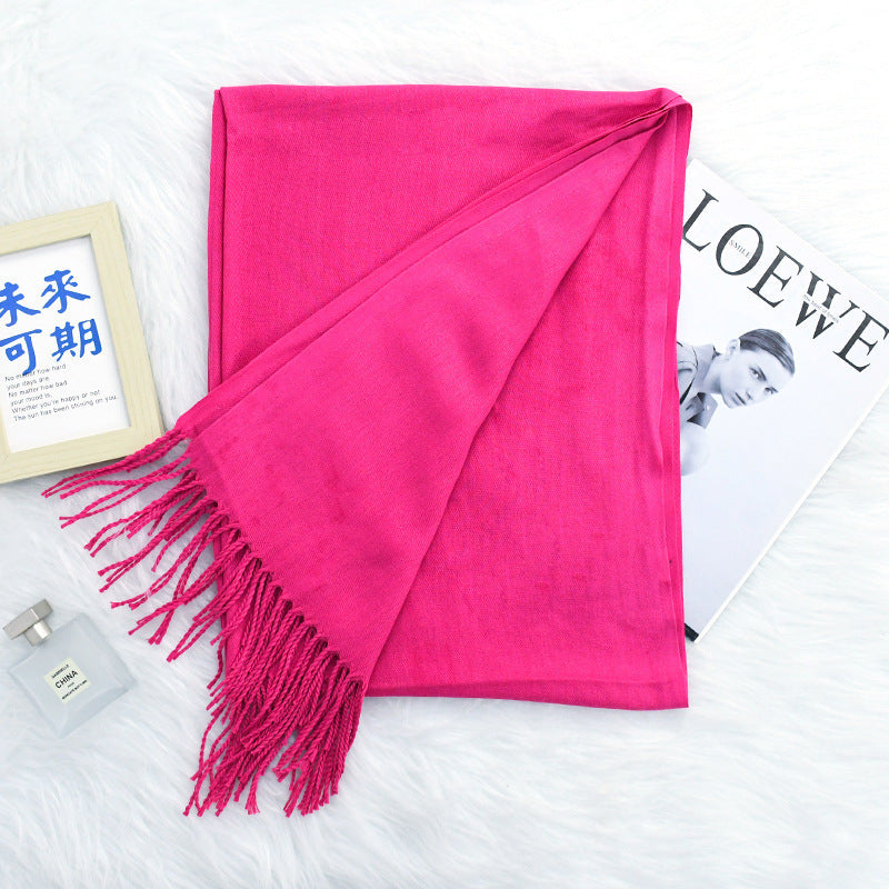 Pink scarf with tassels on a white surface