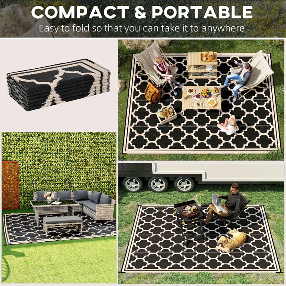 Reversible outdoor rug folded stack with black-and-cream quatrefoil pattern