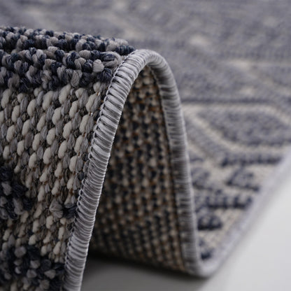 Rug corner with braided gray-and-white edge trim and short fringe