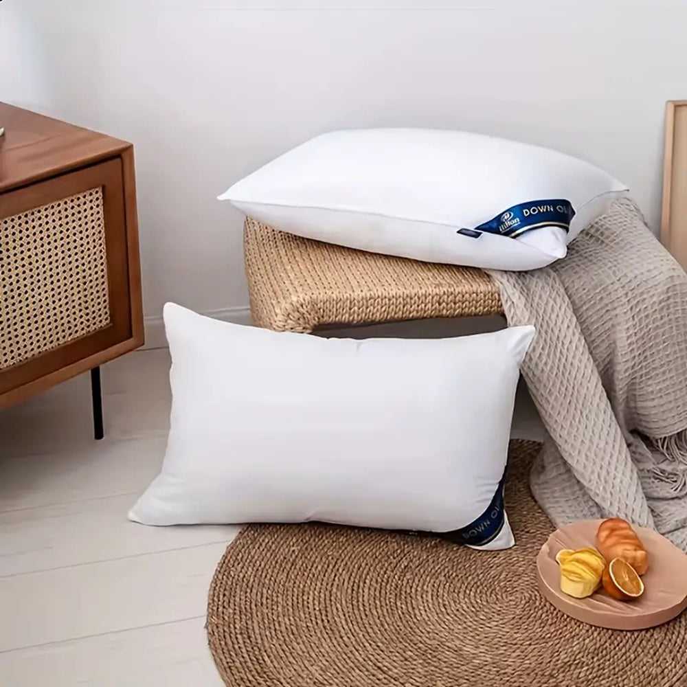 Set of white bed pillows stacked on beige bedding, blue tags visible