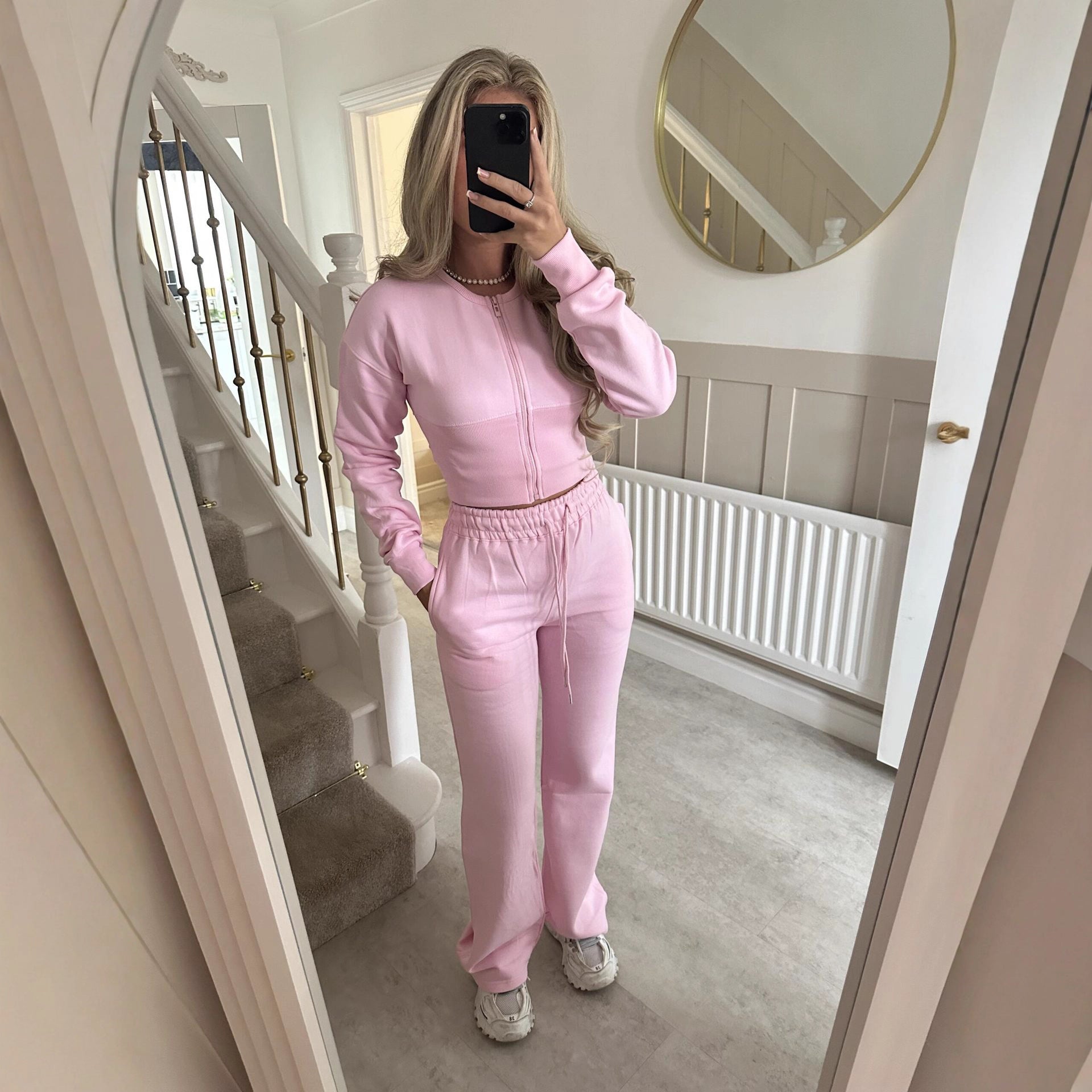 Women’s zip-front sweatshirt and jogger set in pastel pink, two-piece outfit.